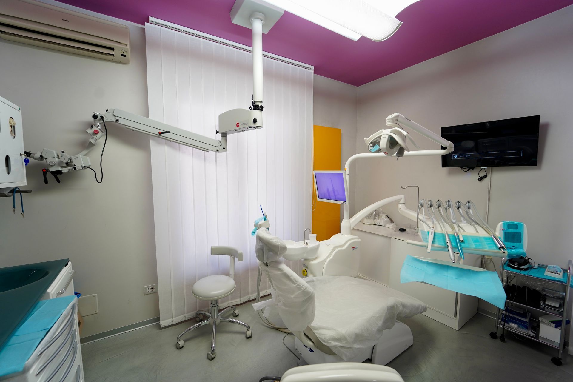 Studio dentistico con poltrona odontoiatrica, attrezzatura e monitor.