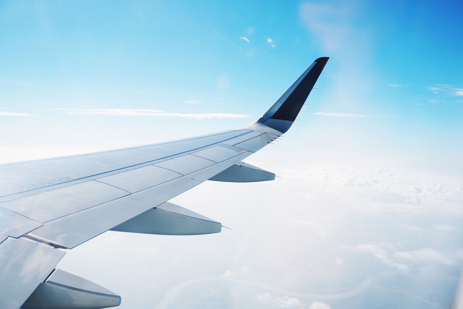 The wing of an airplane is flying in the sky.