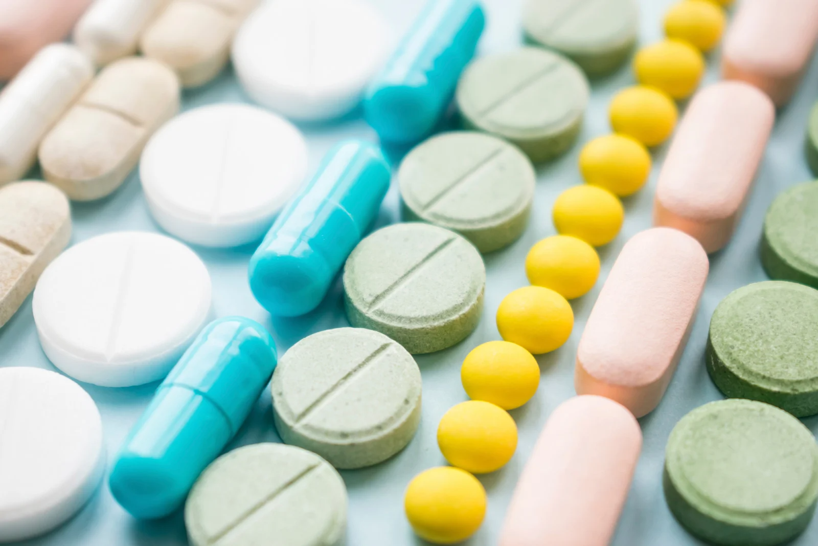 A variety of pills and capsules are lined up on a table.