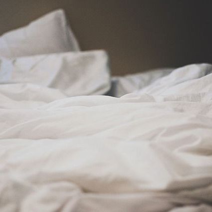Close-up of rumpled white bed sheets and pillows on a bed.