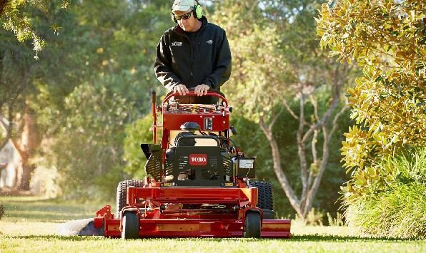 A Man Is Riding A Red Lawn Mower On A Lush Green Lawn – Caboolture, QLD - R & R Hire Services