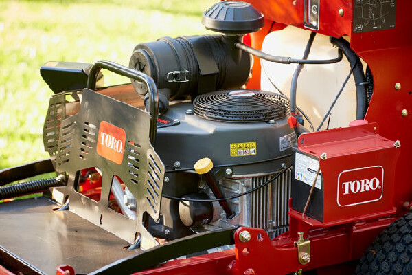 Red Toro lawn mower engine with air filter, fuel tank, and safety shield.
