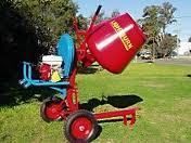 Red concrete mixer on wheels, outdoors on grass.