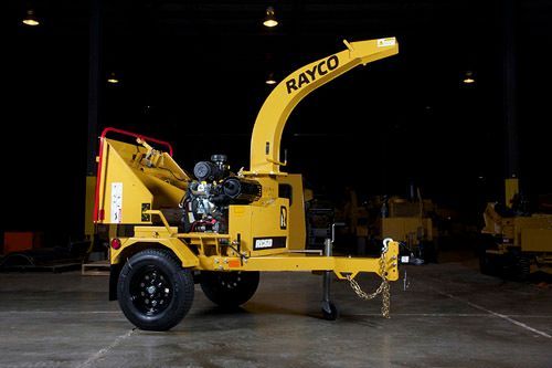 Yellow Rayco wood chipper on a trailer, in a dark warehouse setting.