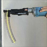 A person using a drywall screw gun to attach screws to a wall; the gun is black and blue with a long strip of yellow screws.