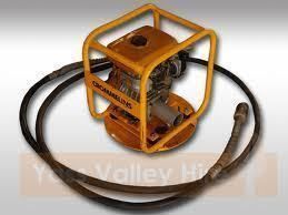 Yellow concrete vibrator with protective cage and attached hose.