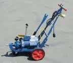 Blue and red road paint machine with a motor and cart, on a concrete surface.