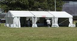 White tent set up on a grassy field, with people inside.