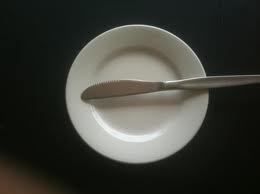 White plate with butter knife on a dark surface.