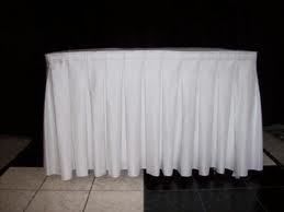 White tablecloth with pleated skirt, covering a table. Black background.
