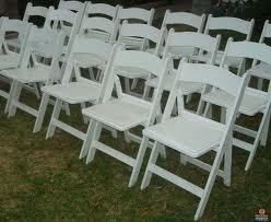 White folding chairs set up on grass, ready for an event.