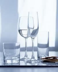 Four clear water glasses, including a wine glass and a champagne flute, sit on a reflective surface.