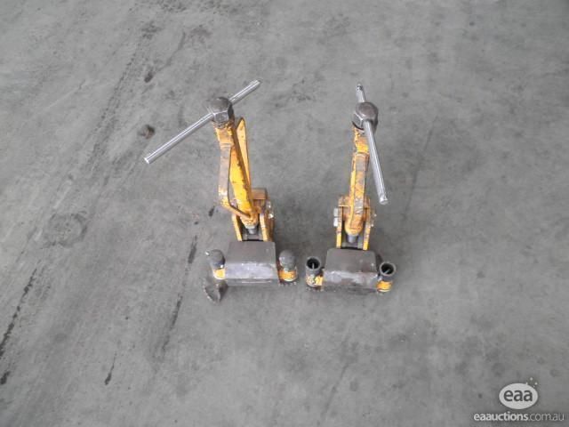Two yellow magnetic welding clamps on a concrete floor.