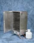 Stainless steel drying chamber with open door, numerous trays, and white jug.