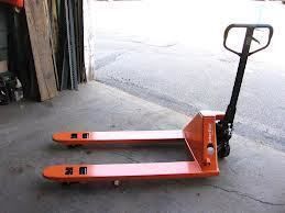 Orange pallet jack on a concrete floor, in a warehouse setting.