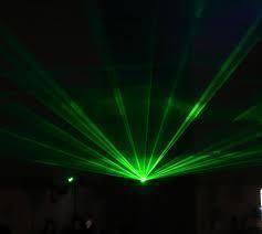 Green laser beams radiating from a central point in a dark room.