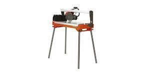 Orange tile saw on metal legs, with a circular blade and a black motor, ready to cut.