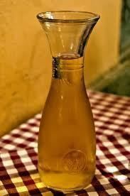 A glass carafe filled with amber liquid, likely wine, on a checkered tablecloth.