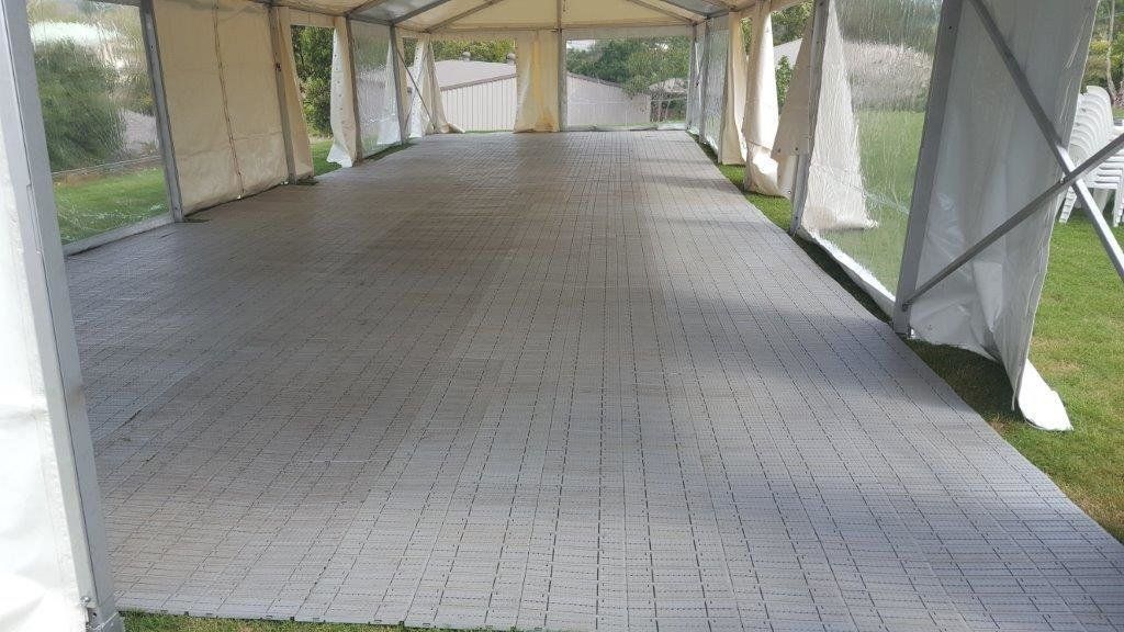 A tent interior with a gray tiled floor, set up on grass.