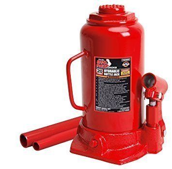 Red hydraulic bottle jack with handle and pump, resting on a surface.