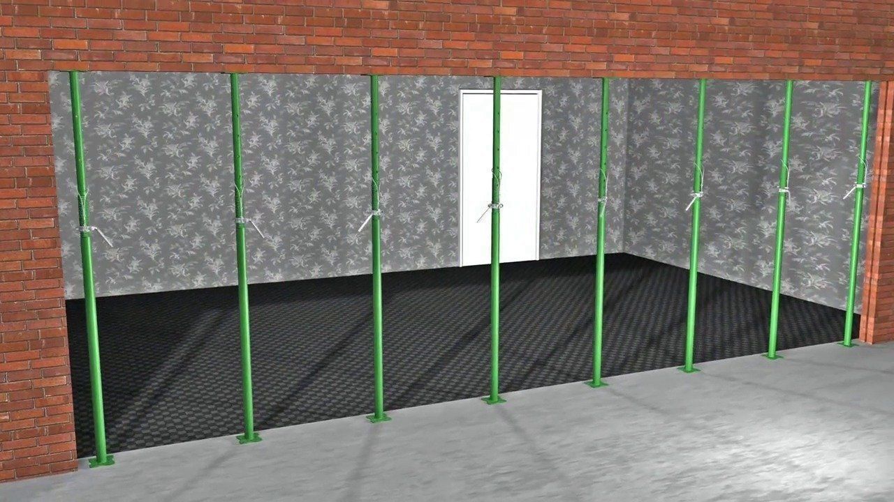 Interior view of a room with temporary green support poles. A doorway is in the center.