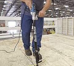 Man using a Quik Drive tool to install fasteners into a floor in a warehouse.