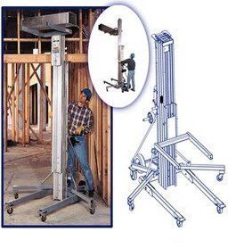 Man operating a silver lift in a construction setting, holding a panel to install.