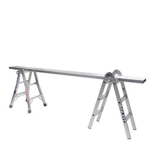 Two aluminum A-frame ladders support a long metal plank, creating a temporary work surface.