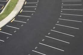 Parking lot with numbered parking spaces, black asphalt, curved layout.