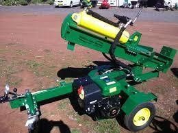 Green and yellow log splitter with a gas engine, on wheels, outdoors.