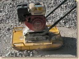 Yellow plate compactor compacting gravel; Honda engine.