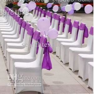 Rows of white chairs draped with purple fabric and balloons, set up for an event.