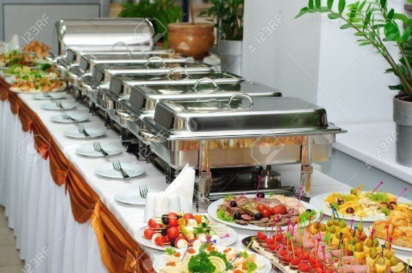 Buffet with chafing dishes and various food platters on a long table set for an event.