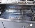 Open commercial dishwasher with metal racks and interior.