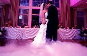 Bride and groom first dance with fog on the dance floor. Purple lighting and drapes frame the scene.