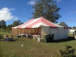 Large red and white striped tent set up on a grassy lawn under a blue sky.