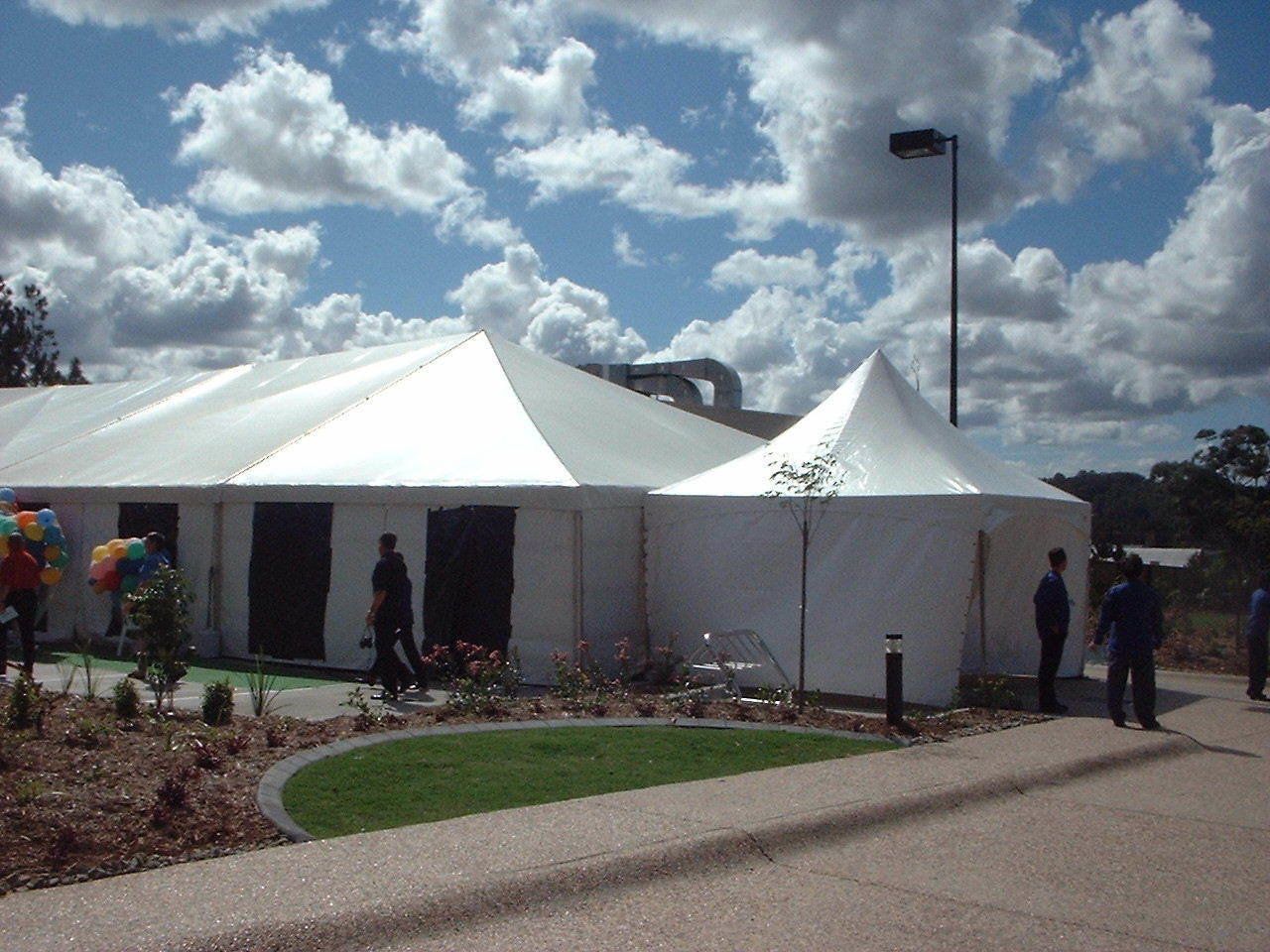 White tent with people gathered outside on a sunny day.
