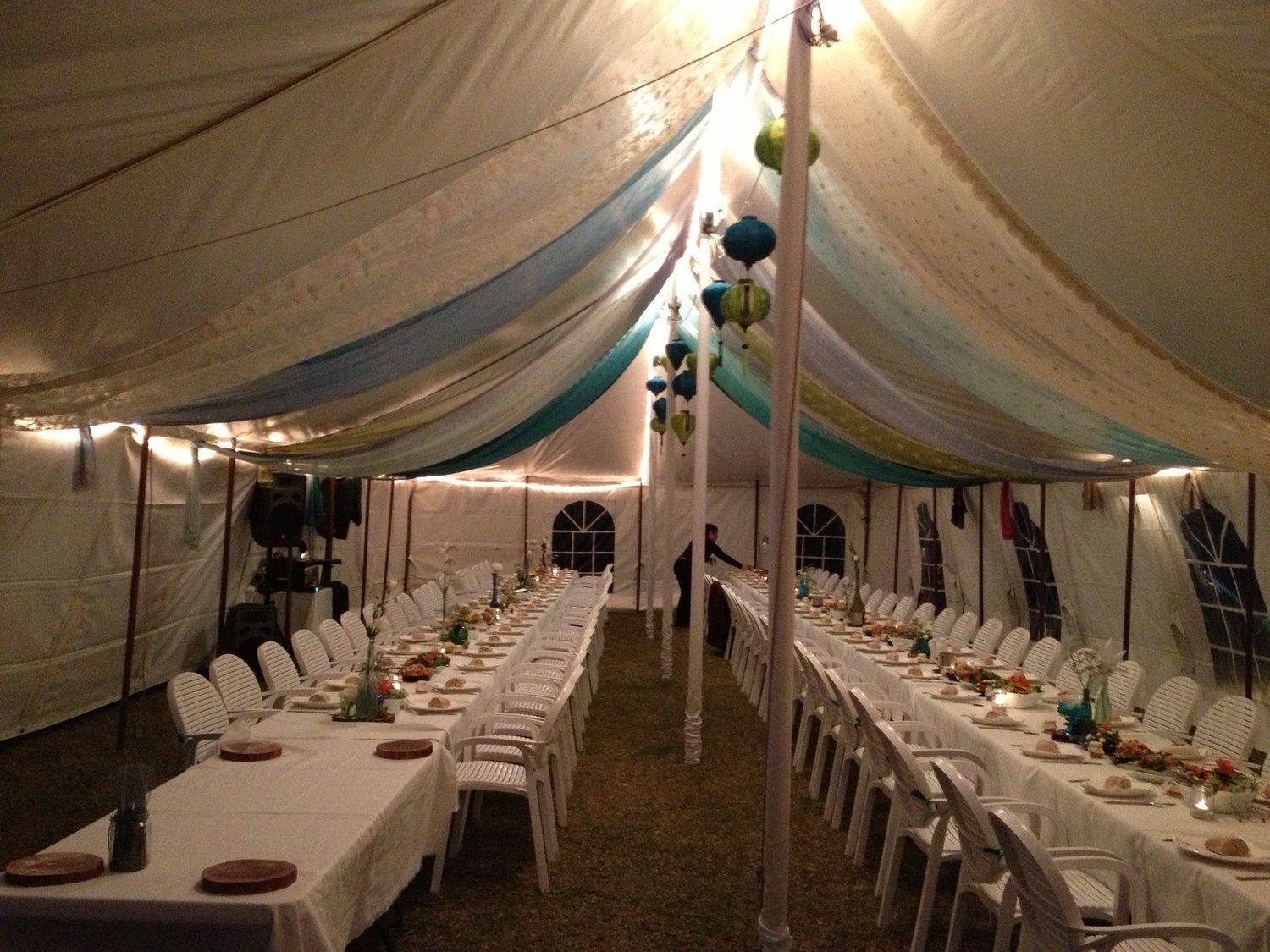 Long tables set for a banquet inside a decorated tent.