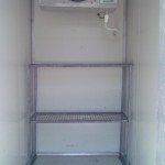 Interior of a refrigerator with metal shelves, a temperature gauge, and a white interior.