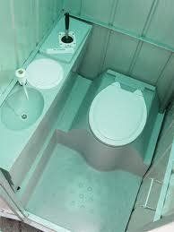 Interior of a portable toilet with a sink, toilet, and light green walls.