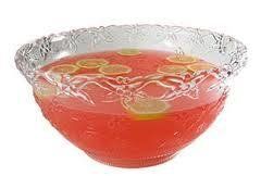 Punch bowl filled with red liquid and lemon slices. Clear bowl with decorative rim.