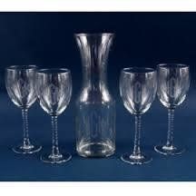 Five wine glasses and a carafe on a dark blue surface.