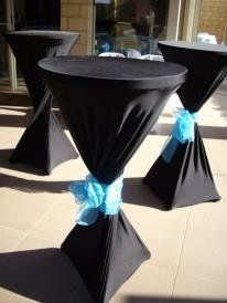 Black cocktail tables with blue ribbon accents, outside.