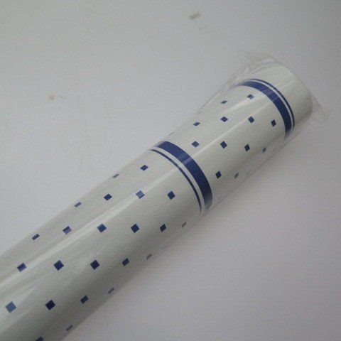 Roll of white wrapping paper with blue square dots and stripes.