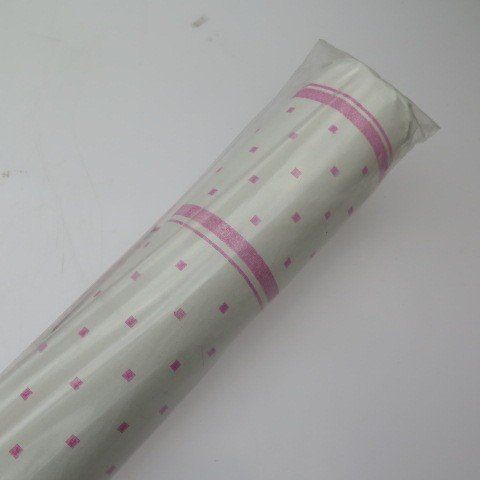 Roll of white wrapping paper with pink squares and stripes, wrapped in plastic.