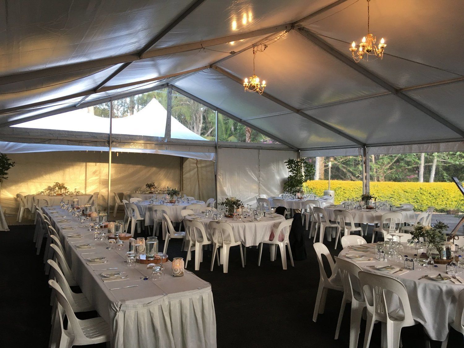 White tent set up for a wedding reception, with tables, chairs, and decorations.