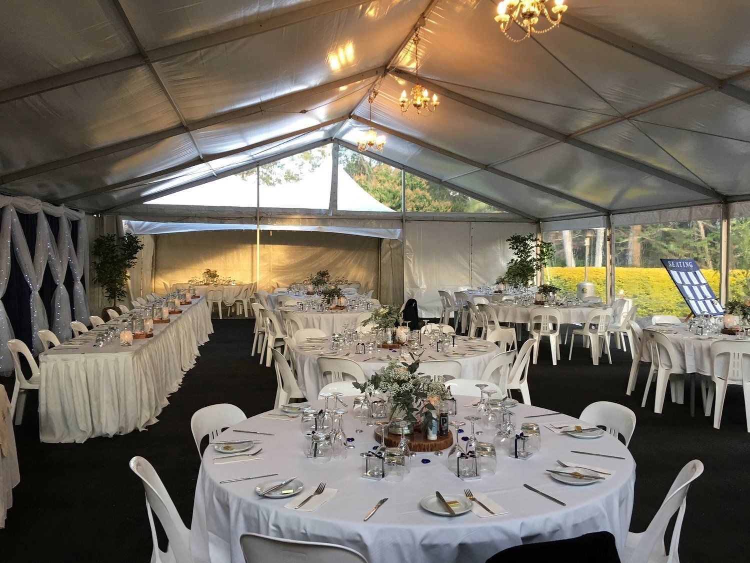 A decorated outdoor event space with round and rectangular tables set for a gathering.