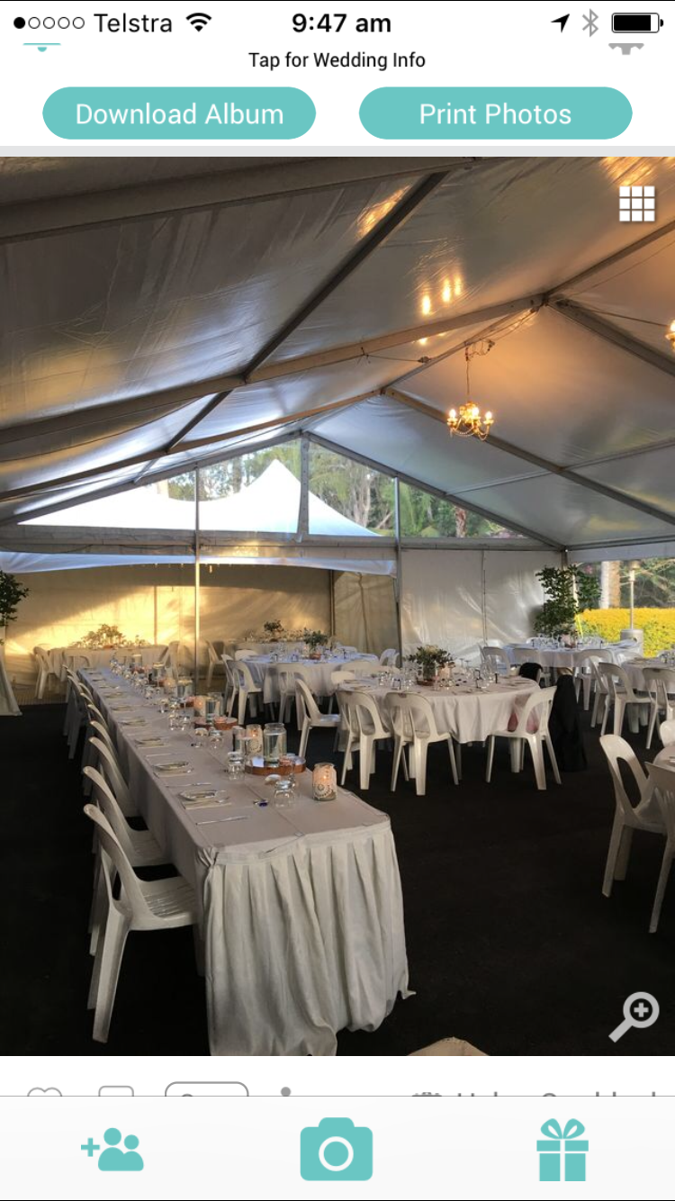 Wedding reception tent, white tables and chairs, strung with lights.