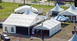 White tents of various sizes and shapes set up on green grass for an event.