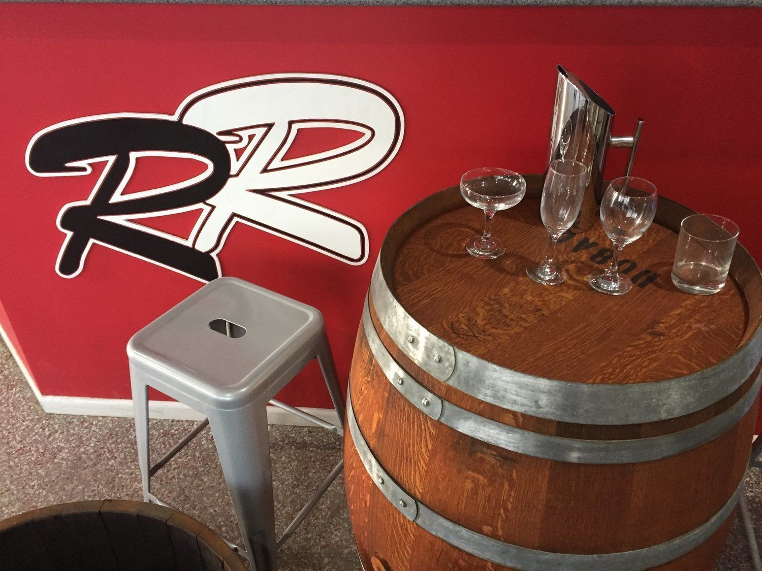 Barrel bar with glassware and stool, red wall with 